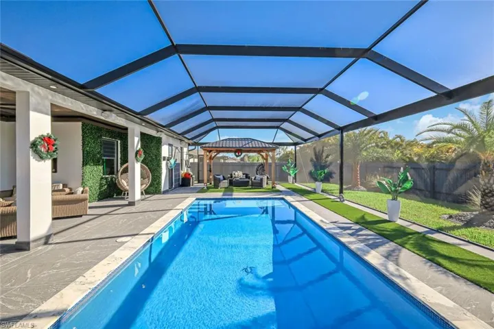 View of swimming pool featuring a fenced backyard, glass enclosure, outdoor lounge area, a fenced in pool, and a patio area