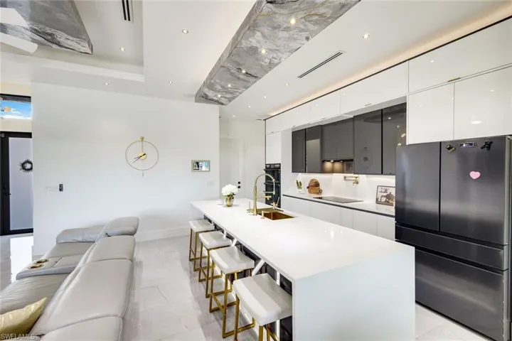 Kitchen with a breakfast bar area, a large island, white cabinets, black appliances, and modern cabinets
