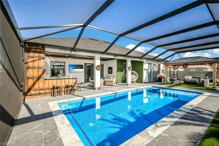 View of pool with a lanai, a patio area, outdoor dry bar, and an outdoor hangout area