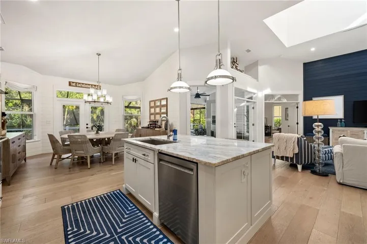 Kitchen with sink, decorative light fixtures, a center island with sink, dishwasher, and white cabinetry
