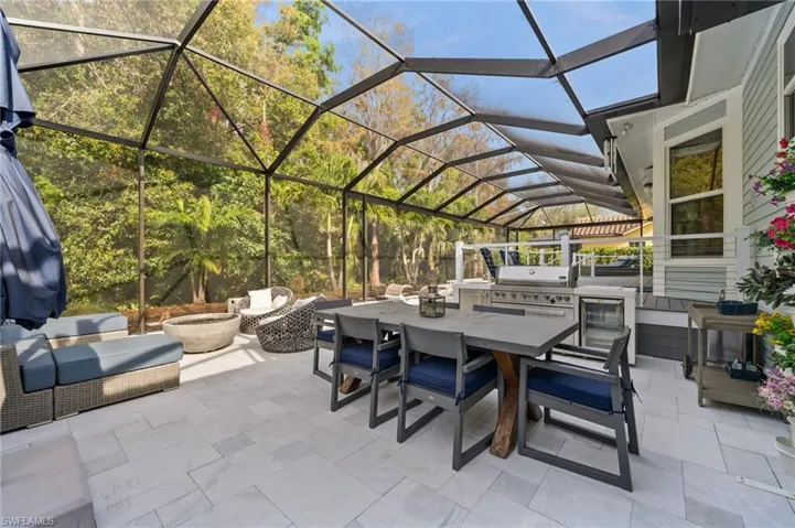 View of patio with area for grilling, glass enclosure, and exterior kitchen