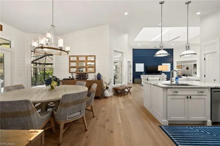 Dining area with light wood-type flooring, a skylight, wood walls, and sink