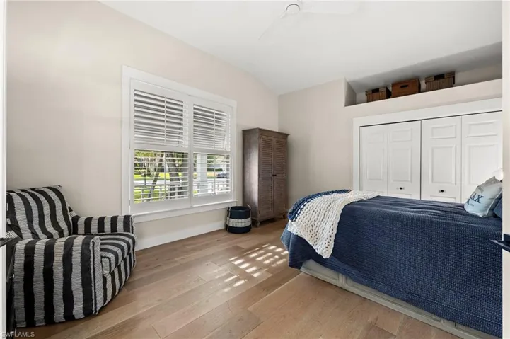 Bedroom featuring a closet, ceiling fan, light hardwood / wood-style flooring, and lofted ceiling