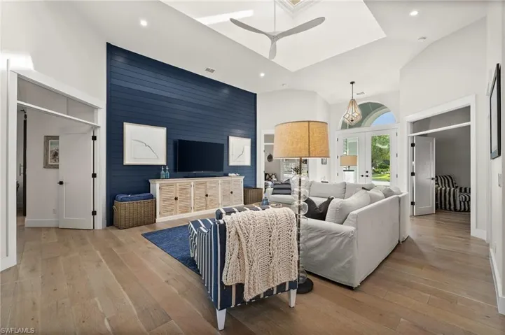 Living room featuring ceiling fan, french doors, high vaulted ceiling, and light hardwood / wood-style floors