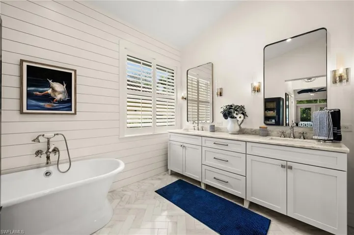 Bathroom with a bathing tub, wooden walls, plenty of natural light, and lofted ceiling