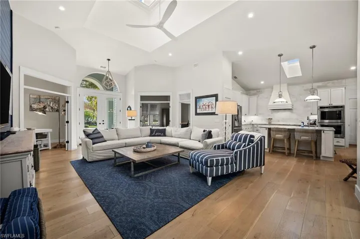 Living room featuring high vaulted ceiling, french doors, sink, ceiling fan, and light wood-type flooring