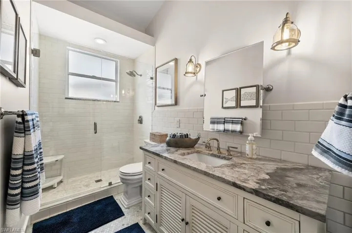 Bathroom with vanity, tile patterned flooring, toilet, tile walls, and a shower with shower door