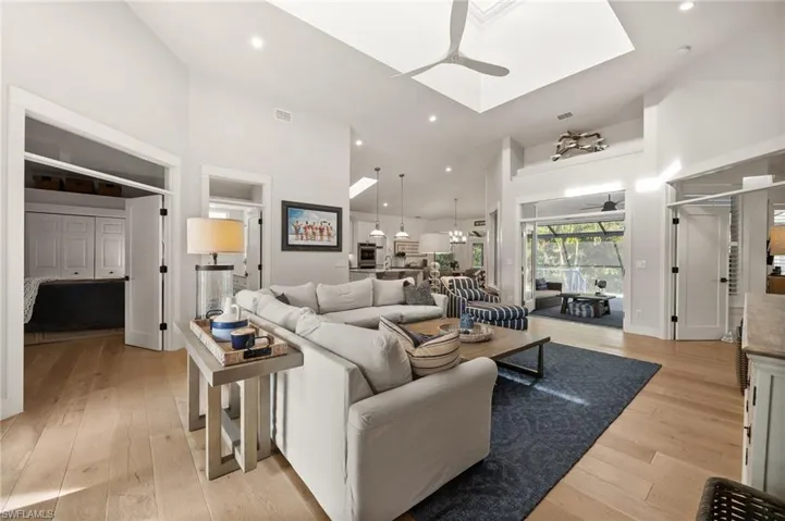 Living room with ceiling fan, light hardwood / wood-style flooring, and high vaulted ceiling