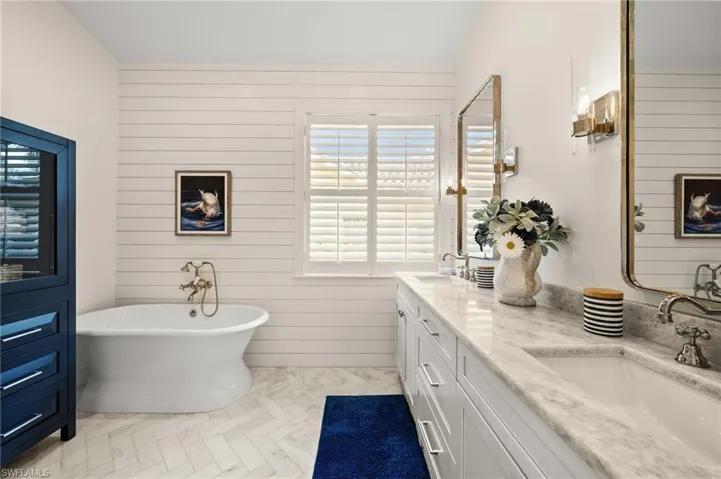Bathroom featuring a bathing tub, wood walls, and vanity