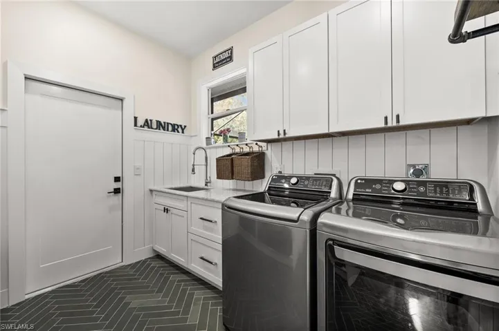 Laundry room with washing machine and clothes dryer, sink, and cabinets