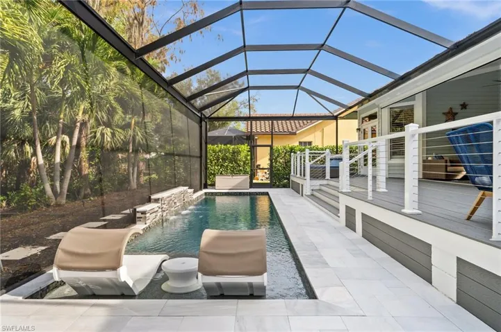 View of swimming pool with glass enclosure, pool water feature, and a patio