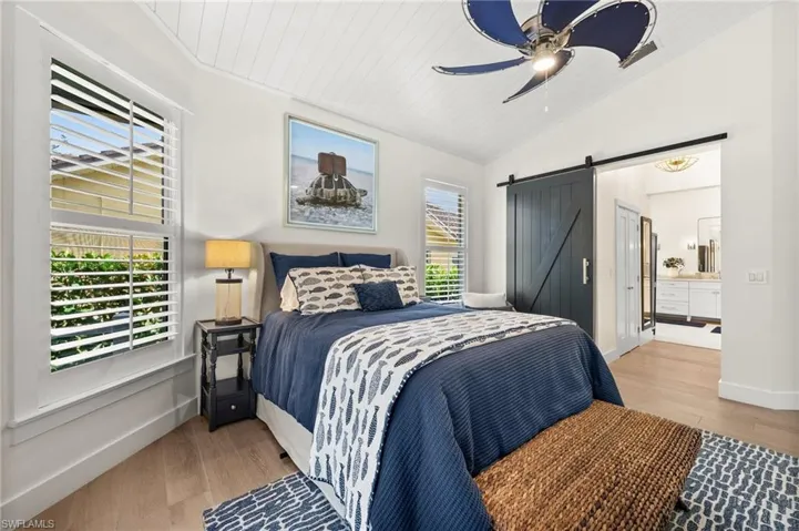 Bedroom with wood ceiling, ceiling fan, wood-type flooring, a barn door, and lofted ceiling