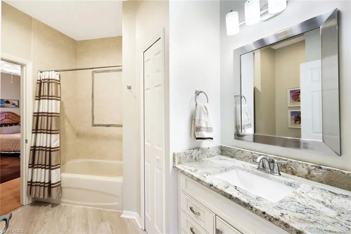 Full bathroom with shower / tub combo, vanity, light wood-style floors, ensuite bath, and a closet