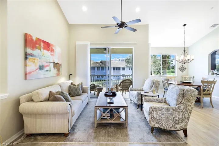 Living area featuring lofted ceiling, hanging lights, wood finished floors, and a ceiling fan