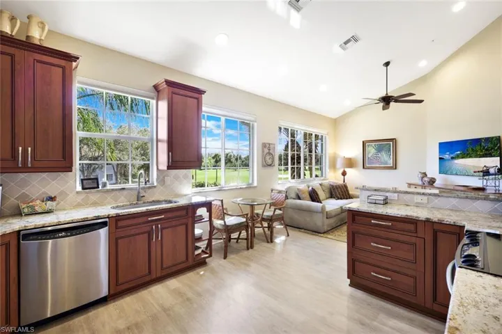 Kitchen with light stone countertops, stainless steel dishwasher, open floor plan, black electric range oven, and light wood-type flooring