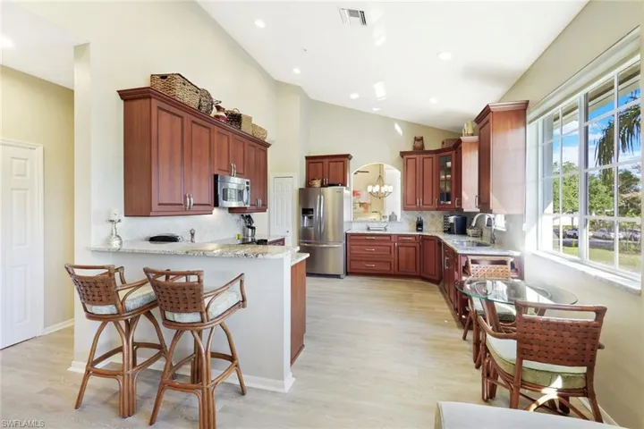 Kitchen with tasteful backsplash, a peninsula, light stone counters, stainless steel appliances, and a kitchen breakfast bar