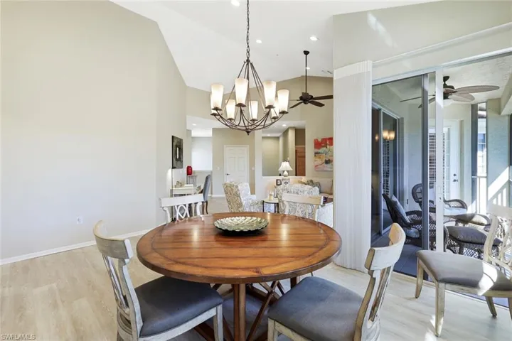 Dining space featuring a ceiling fan, light wood-type flooring, vaulted ceiling, and suspended lighting