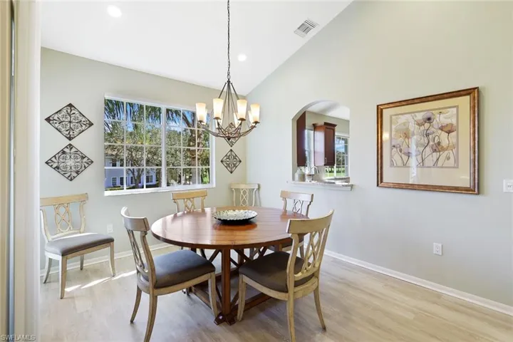 Dining space with lofted ceiling, suspended lighting, healthy amount of natural light, and wood finished floors
