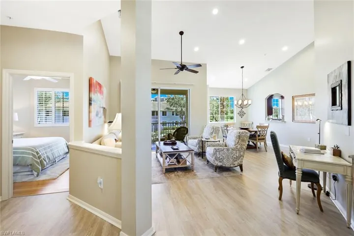 Living area with suspended lighting, light wood-type flooring, a ceiling fan, and vaulted ceiling