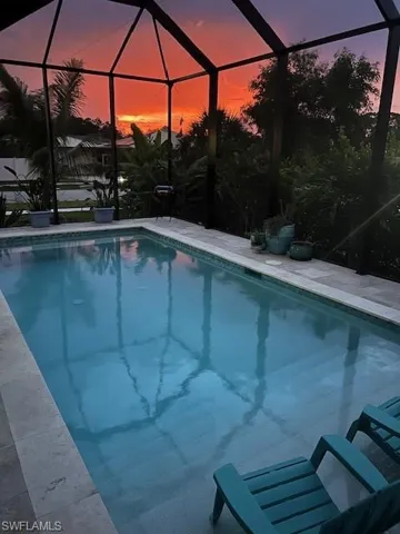 Swimming pool featuring glass enclosure, a sunroom, and a patio area