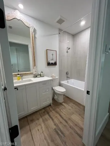 Bathroom with vanity, light wood-style flooring, shower / bath combination, and recessed lighting