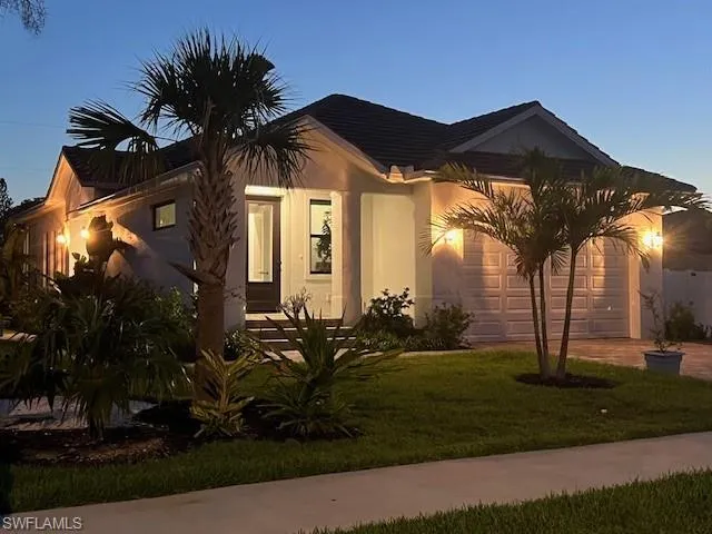 View of front of home featuring driveway, a front yard, stucco siding, and a garage