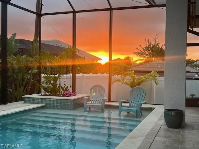 Swimming pool with a fenced backyard, a sunroom, a patio area, and glass enclosure