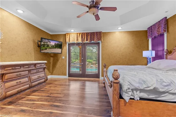 Spacious interior featuring wood-finish flooring, a tray ceiling with recessed lighting, and a ceiling fan