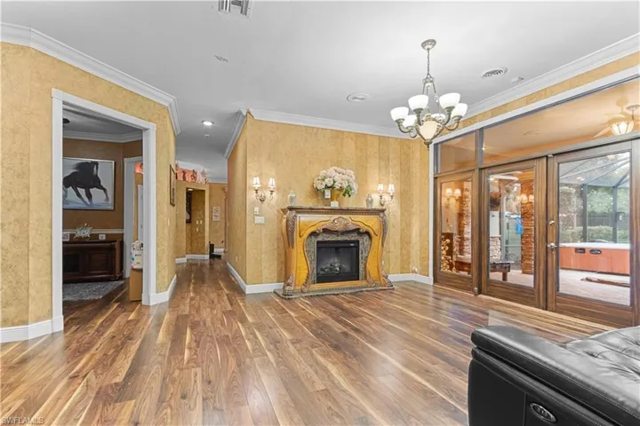 Spacious room featuring wood-finish flooring, an ornate fireplace, and textured wall coverings