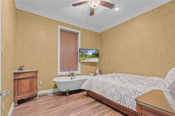 Bedroom featuring wood-finish flooring, textured wall finish, and crown molding