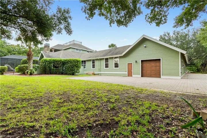 Rear exterior featuring light green siding, a brown garage door, and multiple windows
