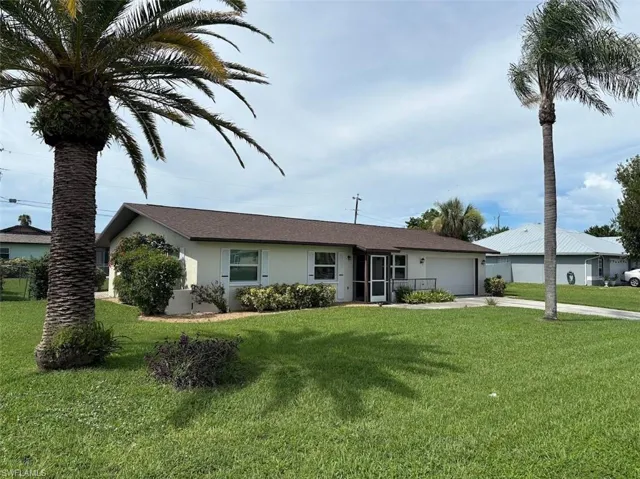 Single story home featuring stucco siding, a front yard, driveway, and a garage