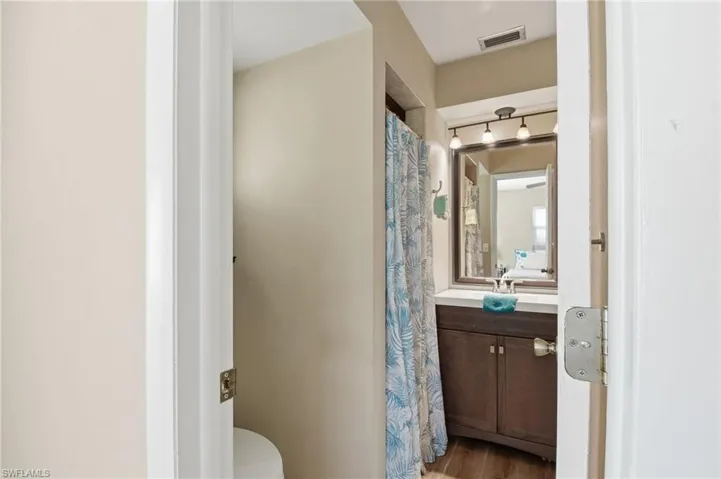 Full bathroom featuring vanity, curtained shower, and light wood-style floors