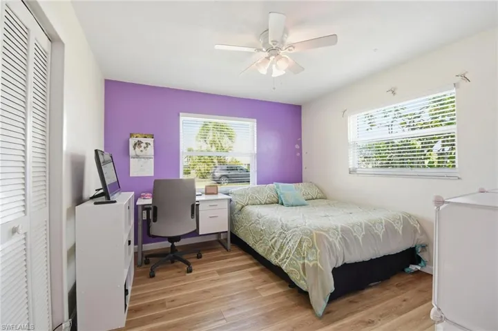 Bedroom with a closet, light wood-type flooring, a ceiling fan, and an office area