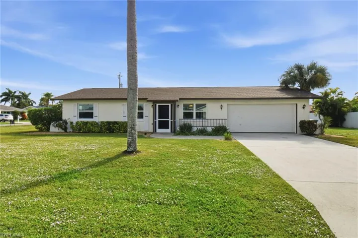 Ranch-style house with driveway, stucco siding, a front yard, and a garage