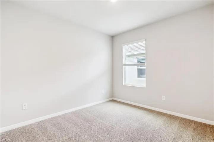 Unfurnished room featuring light carpet and baseboards