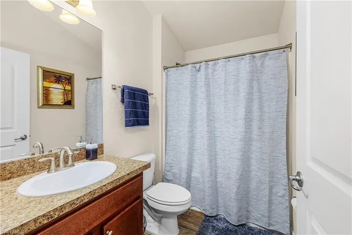 Full bathroom with vanity, curtained shower, dark wood-type flooring, and a textured wall