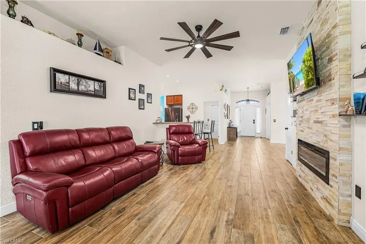 Living room with light wood-style flooring, ceiling fan, and a fireplace