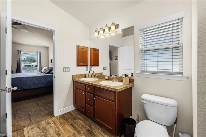 Bathroom featuring double vanity, wood tiled floors, ensuite bath, and lofted ceiling