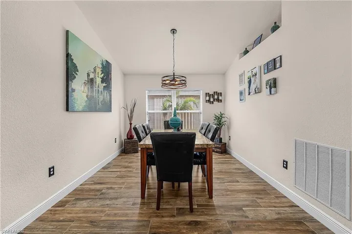 Dining room featuring a textured wall and dark wood-style floors