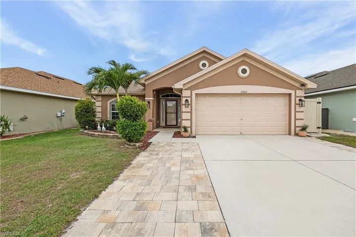 Ranch-style home with stucco siding, a garage, driveway, and a front yard