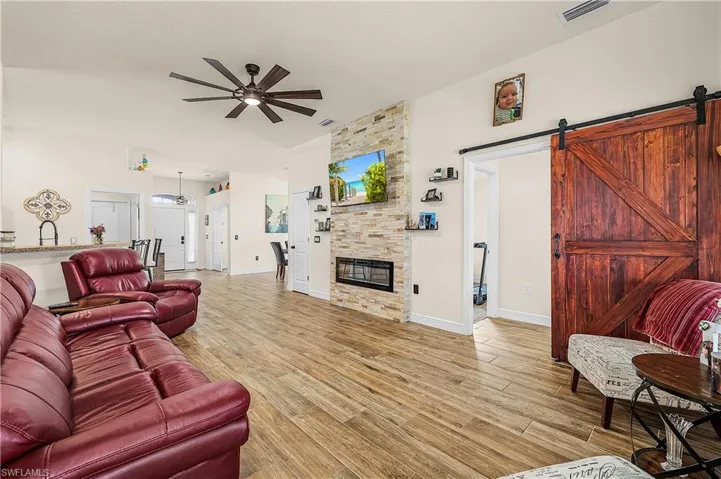Living area featuring light wood-style floors, ceiling fan, a barn door, and a fireplace