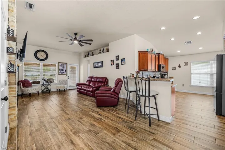 Living area with a ceiling fan, wood tiled floors, healthy amount of natural light, and lofted ceiling