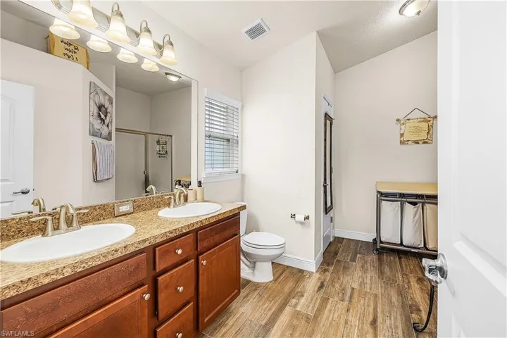 Full bathroom with light wood-style flooring, double vanity, and a shower stall