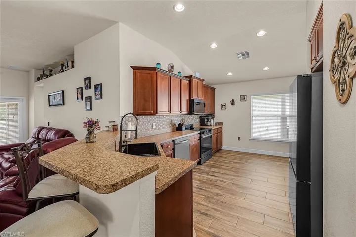 Kitchen with a peninsula, lofted ceiling, a breakfast bar, light wood-style floors, and wood finish cabinets