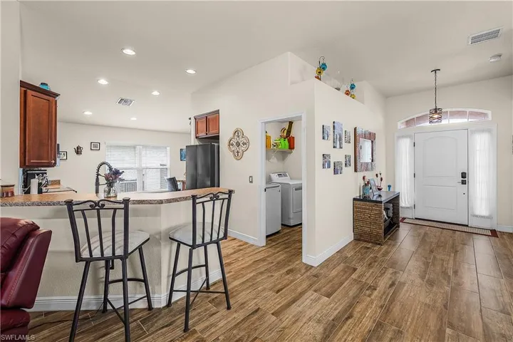 Kitchen featuring a breakfast bar area, a peninsula, dark wood-style flooring, freestanding refrigerator, and light countertops