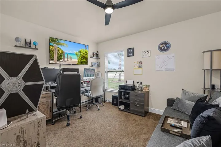 Home office featuring dark colored carpet and a ceiling fan