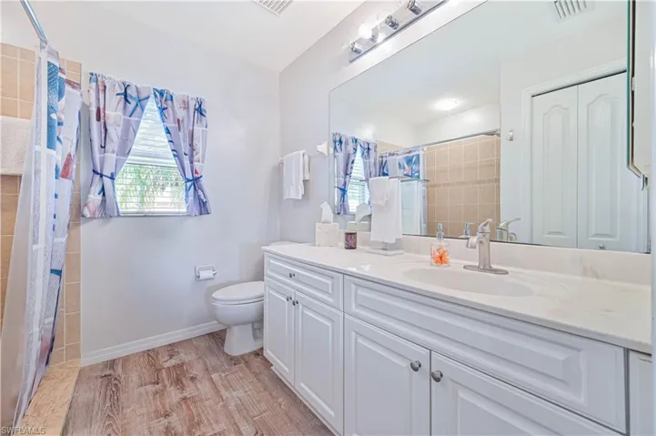 Bathroom with vanity, light wood finished floors, and curtained shower