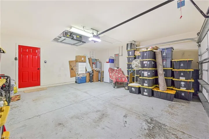 Garage with freestanding refrigerator, a garage door opener, and electric panel