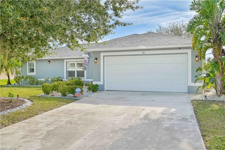 Ranch-style house with stucco siding, a shingled roof, concrete driveway, a front yard, and an attached garage